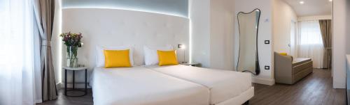 a white bed with yellow pillows in a bedroom at Araba Fenice Hotel in Iseo