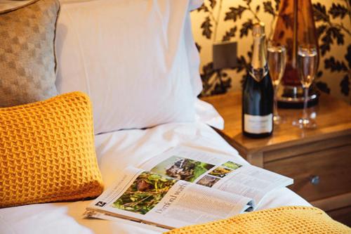 a magazine on a bed with a bottle of wine at The Stag on the River in Godalming