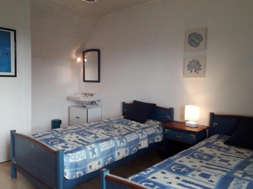 een slaapkamer met 2 bedden en een tafel met een lamp bij MAISON KERLORZ in Bénodet