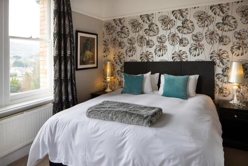 a bedroom with a large white bed with blue pillows at Norbury House Stylish Accommodation in Ilfracombe