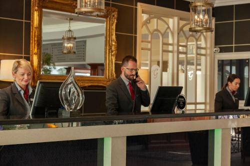 a man talking on a cell phone at a desk at The Gleneagle Hotel & Apartments in Killarney