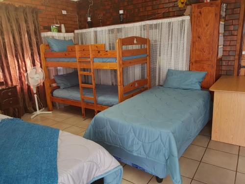 a bedroom with two bunk beds and a kitchen at Cassiandra Place unit 2 in Richards Bay