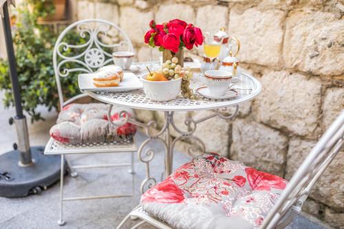 uma mesa com chávenas de café e flores em Emperor's Suites em Split
