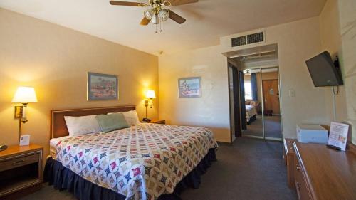 Habitación de hotel con cama y ventilador de techo. en El Rancho Boulder Motel en Boulder City