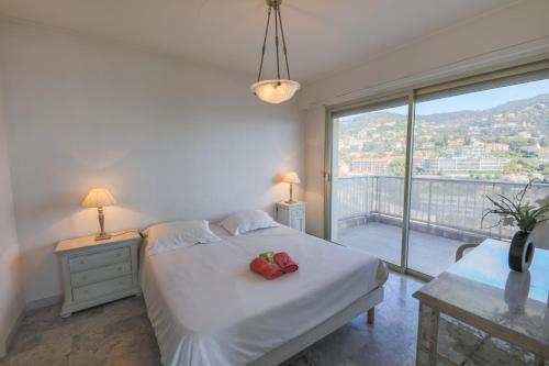 une chambre avec un lit blanc et une grande fenêtre dans l'établissement LE CALIFORNIA - Villefranche-sur-Mer, à Villefranche-sur-Mer