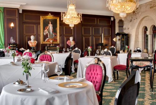 un restaurant avec des tables blanches, des chaises roses et des lustres dans l'établissement Chateau Le Prieuré Saumur - La Maison Younan, à Chènehutte-les-Tuffeaux