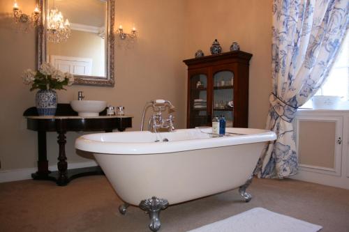 a bathroom with a tub and a sink and a mirror at The Old Parsonage Country House in Berwick-Upon-Tweed
