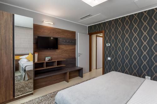 a bedroom with a bed and a flat screen tv at Splendid Conference & Spa Hotel – Adults Only in Mamaia