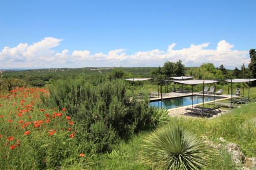 une maison avec une piscine dans un champ de fleurs dans l'établissement Les Esplanes, à La Garde-Adhémar