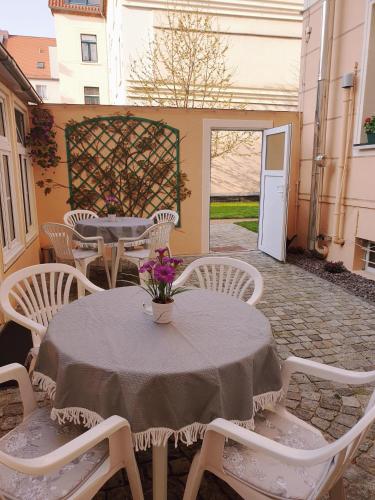 una mesa con sillas blancas y un jarrón de flores. en Pension Giesserstrasse Leipzig, en Leipzig