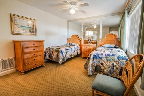 a bedroom with two beds and a dresser and a mirror at Coral Reef Resort, a VRI resort in St. Pete Beach