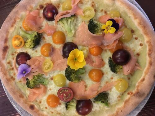 a pizza with broccoli and grapes and flowers on it at Residence Al Barcon in Sarcedo