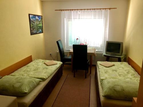 ブルノにあるGalas ubytovani v soukromiのベッド2台、テーブル、窓が備わる客室です。