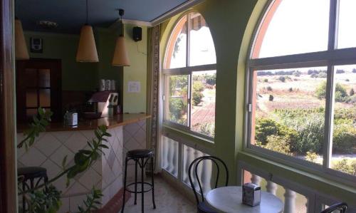 cocina con 2 ventanas, mesa y sillas en Hostal Europa en Estepona