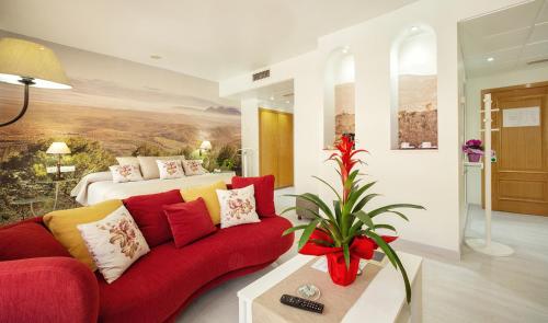 a living room with a red couch and a bed at Hotel Torrepalma in Alcalá la Real