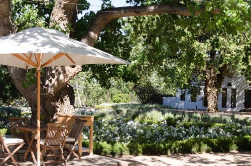 a table and chairs under an umbrella in a garden at La Paris Estate in Franschhoek