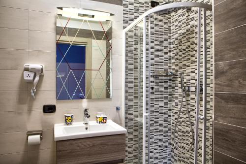 een badkamer met een wastafel en een douche met een spiegel bij La Collina dei Ciliegi in Salerno