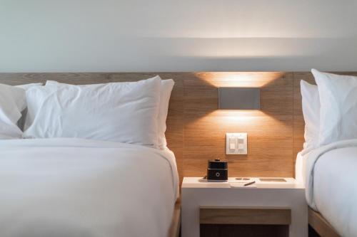 two beds with white pillows and a nightstand between them at Hôtel du Domaine, centre de villégiature et de congrès in Thetford Mines