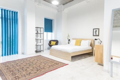 a white bedroom with a bed and a chair at Concierge Downtown in Athens