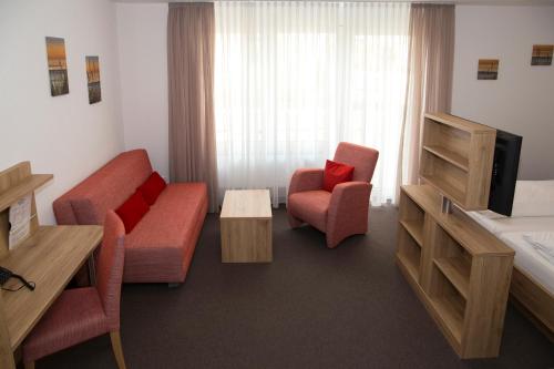 a living room with a couch and two chairs and a television at Hotel Gasthof Schützen GbR in Laupheim