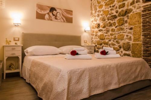 una camera da letto con un letto con asciugamani e un muro in pietra di La casa di Chiara a Siracusa