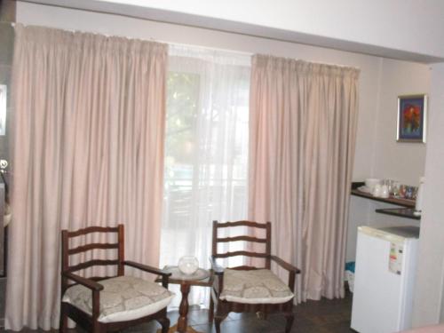 a living room with two chairs and a table and a window at Ukarimu Guest House in Klerksdorp