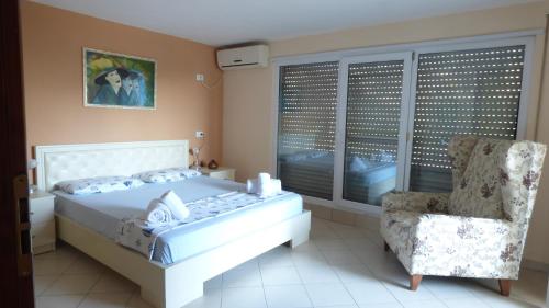 a bedroom with a white bed and a chair at Duplex in Durrës