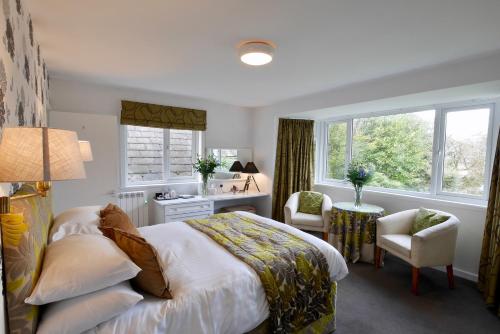 a bedroom with a bed and a desk and two windows at Selkirk Arms Hotel in Kirkcudbright