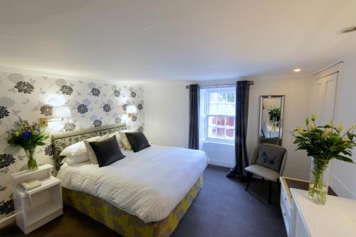 a bedroom with a large bed and a chair at Selkirk Arms Hotel in Kirkcudbright