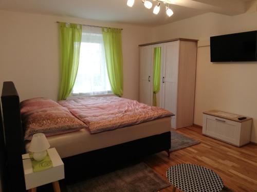 1 dormitorio con 1 cama y una ventana con cortinas verdes en Ferienwohnung Deisenberger en Furth