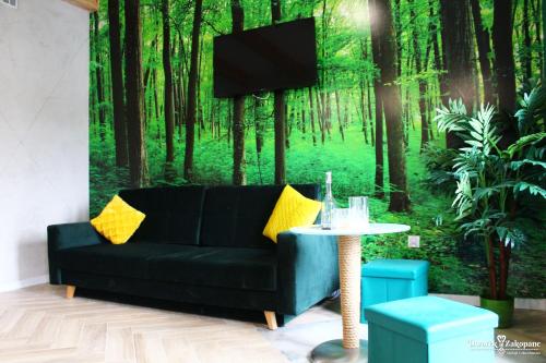 a living room with a couch and a tv in the forest at Dworek Zakopane in Zakopane