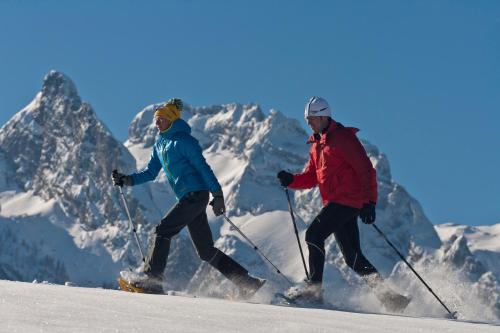 two people are skiing down a snow covered mountain at Gasthaus-Landhotel Traunstein in Abtenau