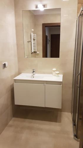 uma casa de banho com um lavatório branco e um espelho. em U Podnóża Zamku em Szczytna