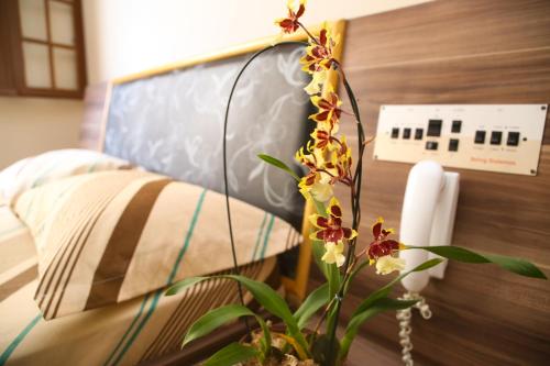 a vase with flowers on a table next to a bed at Hotel Hot Brás in Sao Paulo