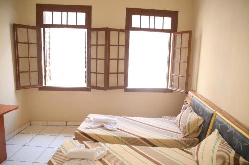 a small room with two windows and a bed at Hotel Hot Brás in Sao Paulo