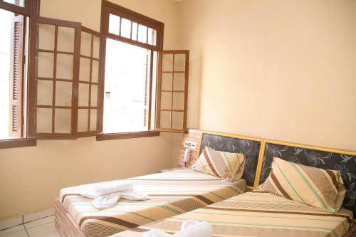 two beds in a room with two windows at Hotel Hot Brás in Sao Paulo