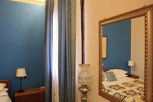 a mirror in a bedroom with a bed and a lamp at Villa Clementine in Piazza Armerina