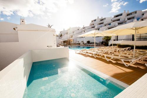 a pool with chairs and umbrellas next to a building at 3HB Golden Beach in Albufeira