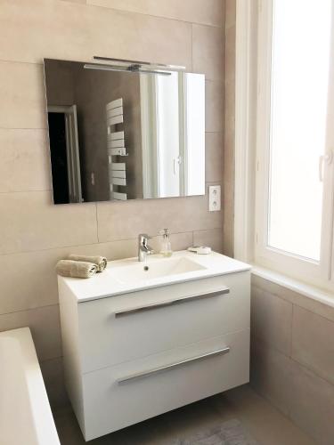une salle de bain blanche avec un lavabo et un miroir dans l'établissement Le Central Wimereux, à Wimereux
