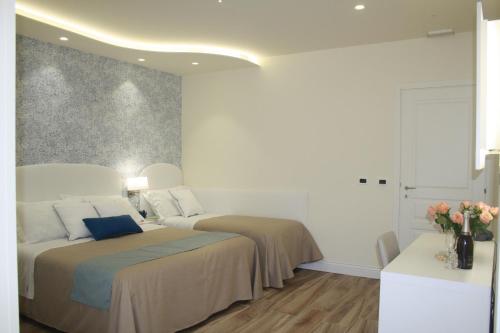 a white bedroom with two beds and a vase of flowers at Ines bed and breakfast in Giardini Naxos