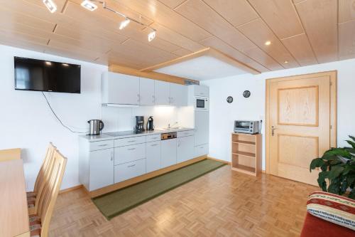 eine Küche mit weißen Schränken und einem TV an der Wand in der Unterkunft Haus Moosmann in Schröcken