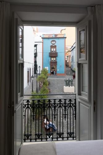 a person sitting on a chair looking out of a window at Hotel Emblemático Holiday Time in Santa Cruz de la Palma