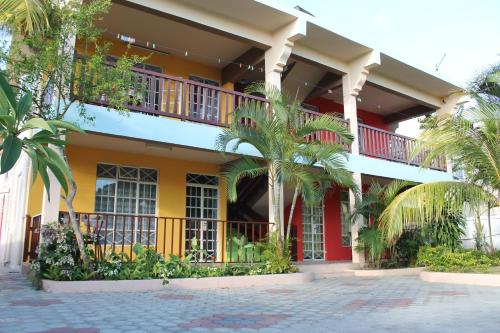 a yellow building with a balcony and palm trees at Residence Devika2 Trou aux Biches in Trou aux Biches