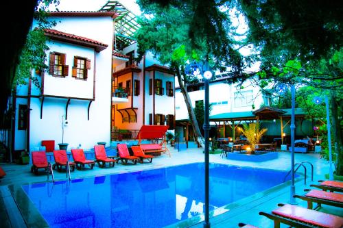 a swimming pool with red chairs next to a building at Kaliptus Hotel in Kemer