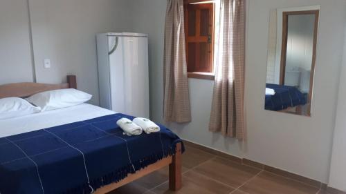 a bedroom with a bed with blue sheets and white pillows at Pousada Kart Clube in São João del Rei