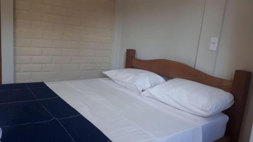 a bed with white sheets and pillows in a room at Pousada Kart Clube in São João del Rei