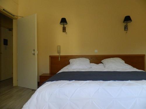 a bedroom with a bed with white sheets and two pillows at Hôtel La Caravelle in Nyons