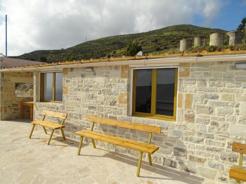 a stone house with two benches in front of it at Gaitani Village in Léntas