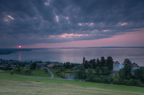 a sunset over the water with a city and a town at Schloss Wartensee in Rorschacherberg
