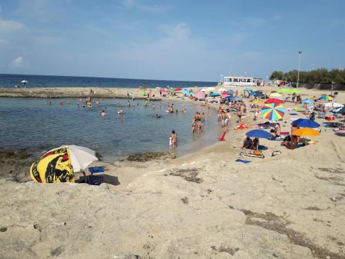 a crowd of people on a beach with umbrellas at Giardino dei Baroni house in Marina di Mancaversa